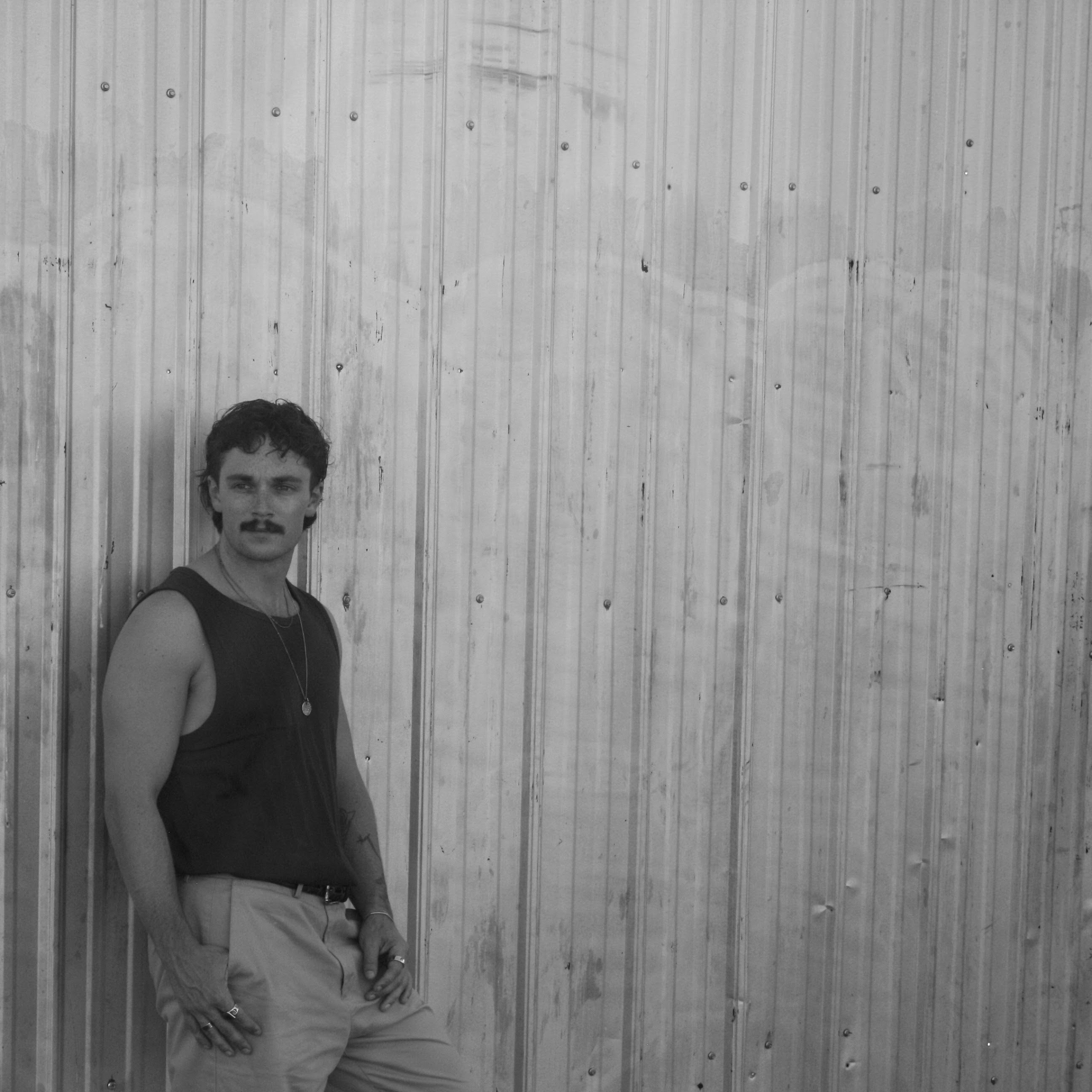 Greyson Turner leaning against a corrugated metal wall